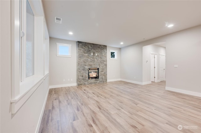 unfurnished living room featuring a tile fireplace and light hardwood / wood-style floors