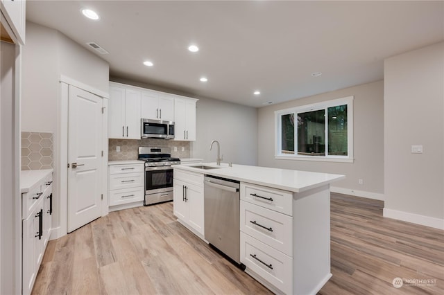 kitchen with white cabinetry, light wood-type flooring, an island with sink, and appliances with stainless steel finishes