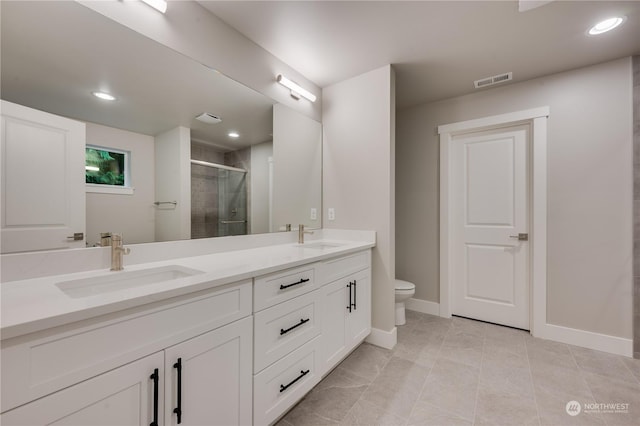 bathroom with a shower with door, vanity, tile patterned floors, and toilet