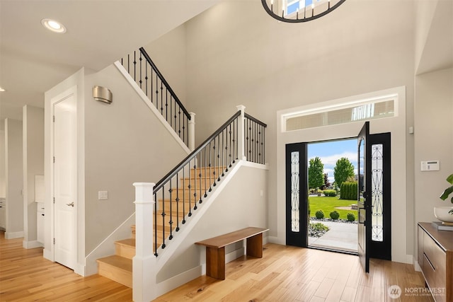 foyer featuring baseboards, stairway, a high ceiling, and wood finished floors