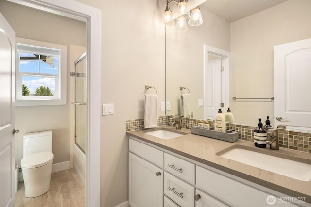 full bathroom with toilet, double vanity, backsplash, and a sink