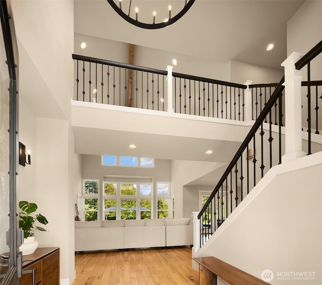 foyer with a healthy amount of sunlight, stairs, a towering ceiling, and wood finished floors