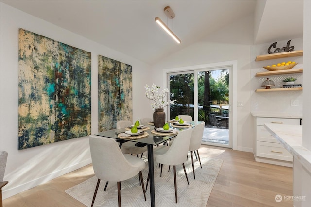 dining area with vaulted ceiling and light hardwood / wood-style flooring