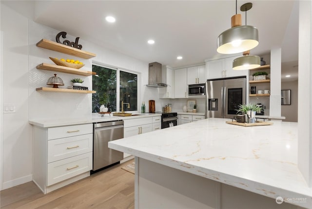 kitchen featuring stainless steel appliances, white cabinetry, wall chimney range hood, and light stone counters