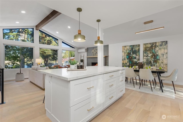 kitchen with pendant lighting, light stone countertops, light hardwood / wood-style floors, and white cabinets