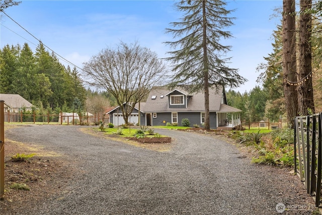 farmhouse with gravel driveway and fence