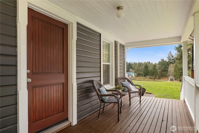 wooden terrace with covered porch and a yard