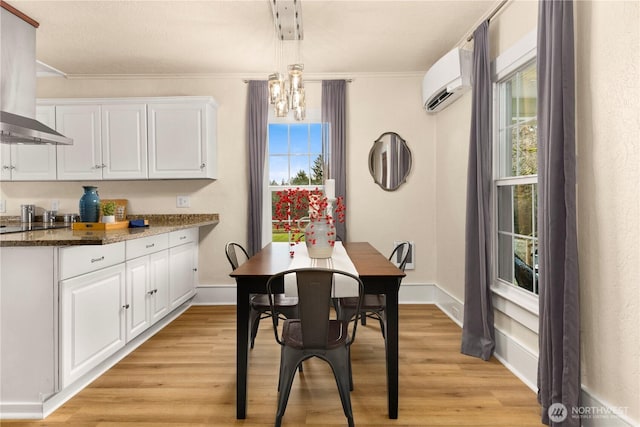 dining space featuring an AC wall unit, ornamental molding, light wood-style floors, baseboards, and a chandelier