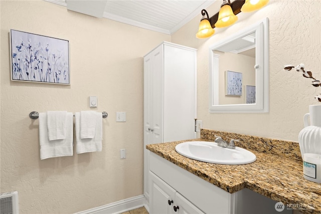 bathroom with baseboards, vanity, a textured wall, and ornamental molding