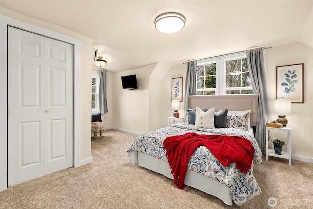 carpeted bedroom with multiple windows, a textured ceiling, baseboards, and vaulted ceiling