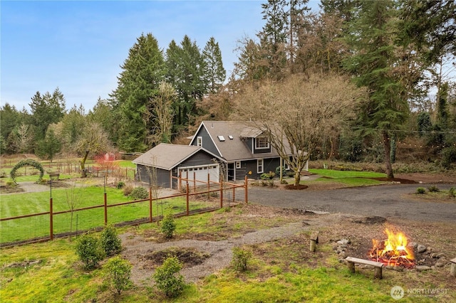 view of front facade featuring a front yard, an outdoor fire pit, dirt driveway, and fence