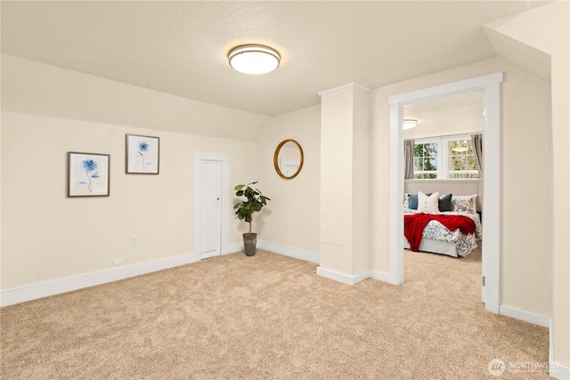 spare room with light colored carpet, baseboards, and lofted ceiling