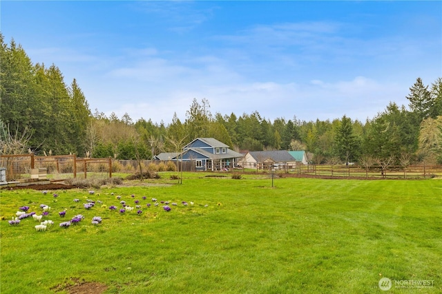 view of yard with a wooded view and fence