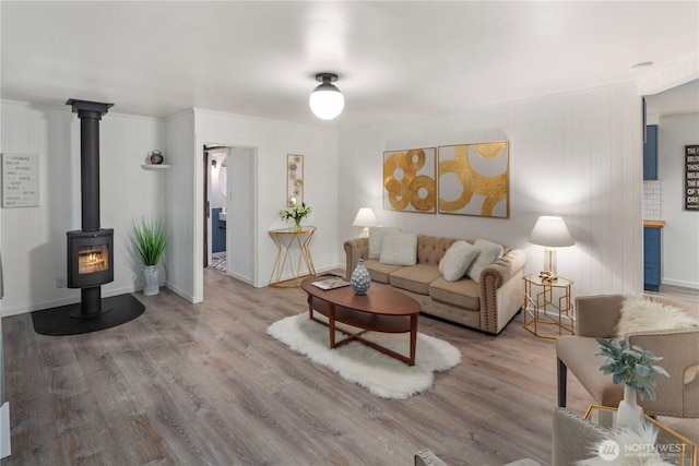 living room featuring a wood stove, baseboards, and wood finished floors