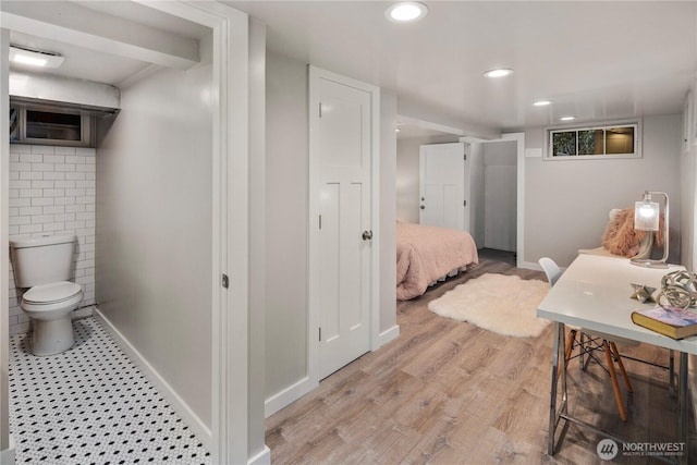 bathroom featuring baseboards, wood finished floors, toilet, and recessed lighting