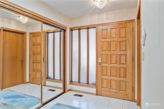 foyer entrance featuring an inviting chandelier and light tile patterned flooring