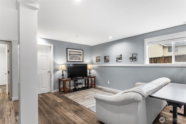 living area featuring dark wood-style floors, decorative columns, and baseboards