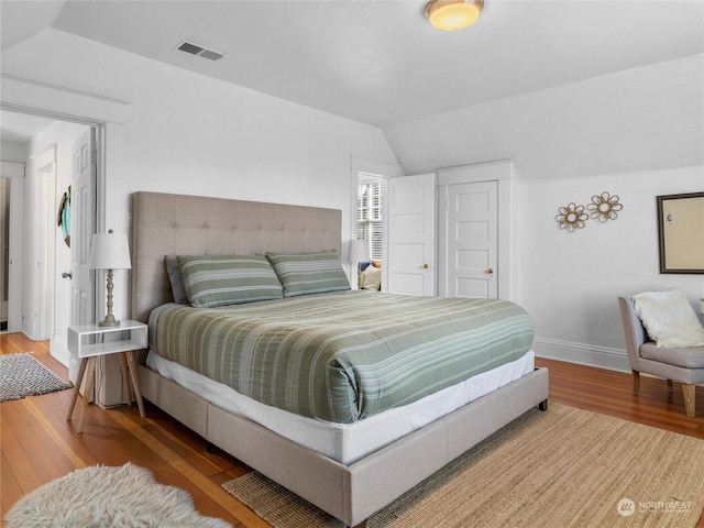 bedroom with lofted ceiling and wood-type flooring