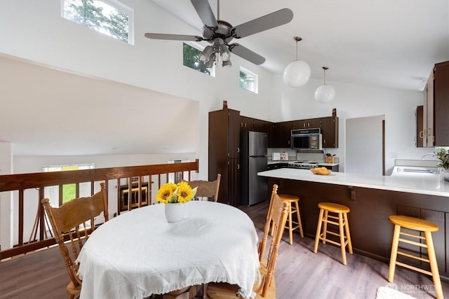 dining area with high vaulted ceiling, sink, and light hardwood / wood-style floors