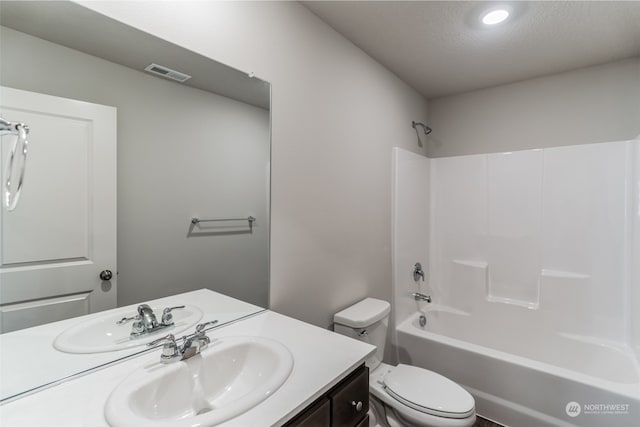 full bathroom with vanity, bathtub / shower combination, a textured ceiling, and toilet