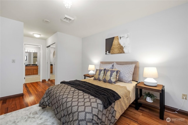 bedroom with hardwood / wood-style floors and ensuite bath