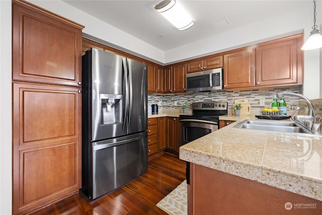 kitchen with pendant lighting, sink, appliances with stainless steel finishes, dark hardwood / wood-style floors, and tasteful backsplash