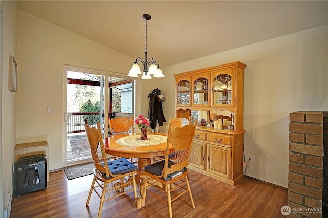 dining room with vaulted ceiling, dark wood-type flooring, and a notable chandelier