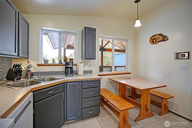 kitchen featuring pendant lighting, sink, gray cabinets, backsplash, and stainless steel dishwasher