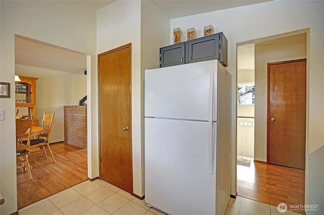 kitchen featuring white refrigerator, gray cabinetry, and light tile patterned floors