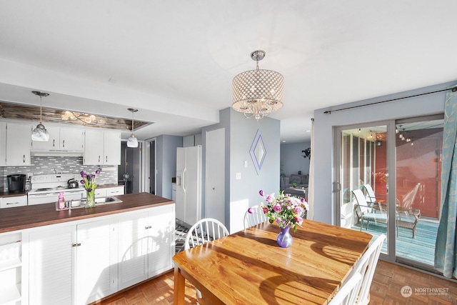 kitchen with butcher block counters, white cabinetry, decorative light fixtures, white appliances, and backsplash