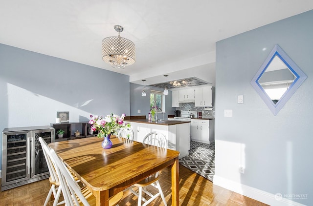 dining room with wine cooler, sink, and a notable chandelier