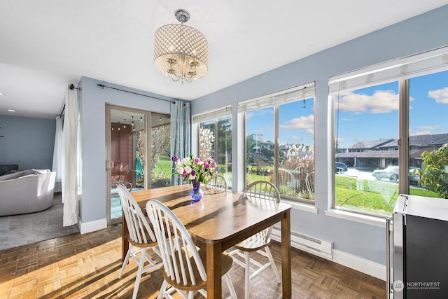 dining space featuring a baseboard heating unit, dark parquet flooring, and a chandelier