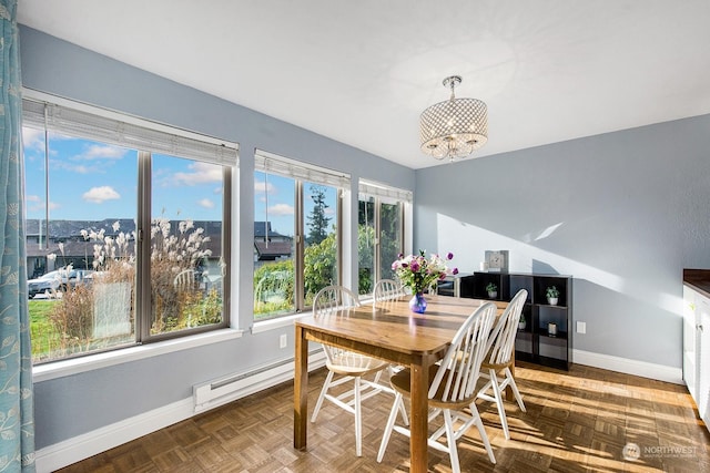 dining area with an inviting chandelier, parquet flooring, and a baseboard heating unit