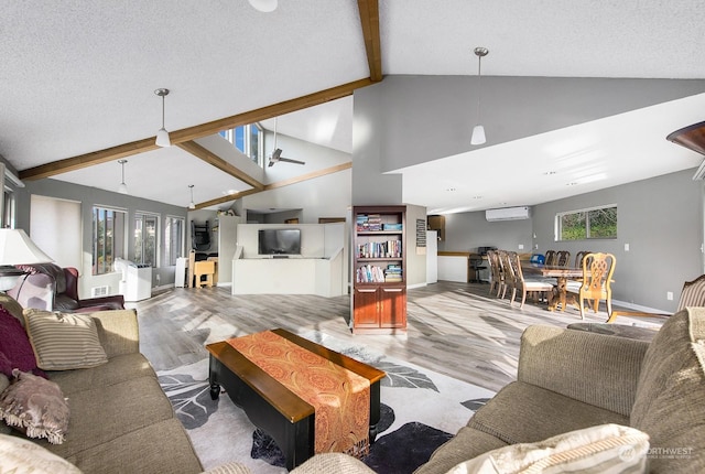 living room featuring a wall mounted air conditioner, a textured ceiling, beamed ceiling, ceiling fan, and light hardwood / wood-style floors