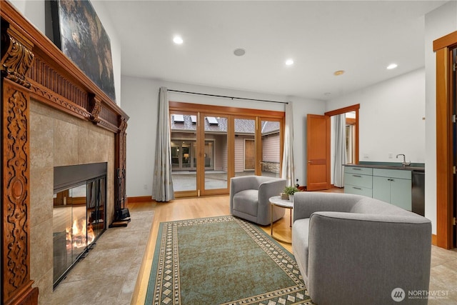 living area featuring light wood finished floors, recessed lighting, baseboards, and a tile fireplace