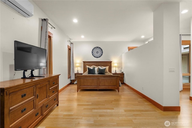 bedroom with baseboards, a wall unit AC, and light wood-style floors