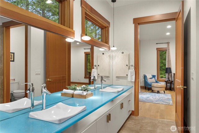 bathroom featuring double vanity, a sink, and toilet