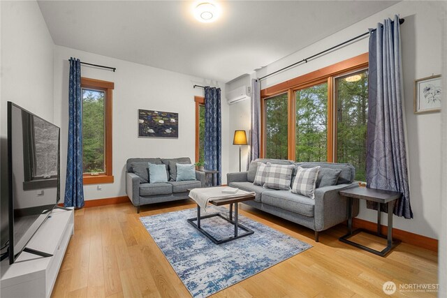 living room featuring a wall mounted AC, wood finished floors, and baseboards