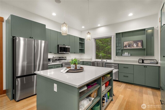 kitchen featuring light wood finished floors, open shelves, appliances with stainless steel finishes, a sink, and green cabinetry