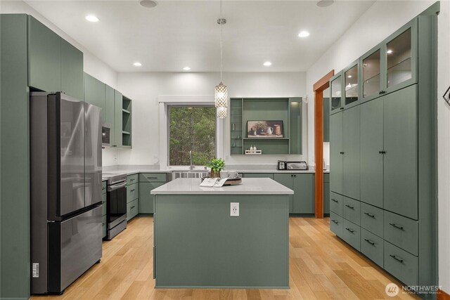 kitchen with stainless steel appliances, open shelves, light wood-style flooring, and green cabinetry