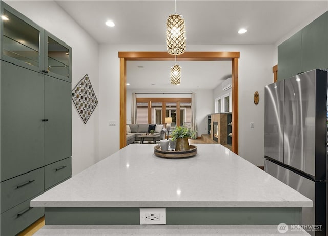 kitchen with recessed lighting, a wall mounted AC, freestanding refrigerator, a center island, and green cabinetry