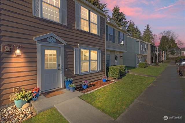 exterior entry at dusk featuring a lawn