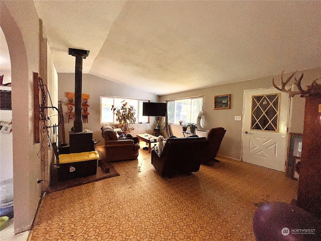 living room featuring lofted ceiling, a textured ceiling, and a wood stove