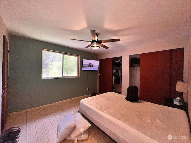 bedroom featuring tile patterned flooring, two closets, and ceiling fan