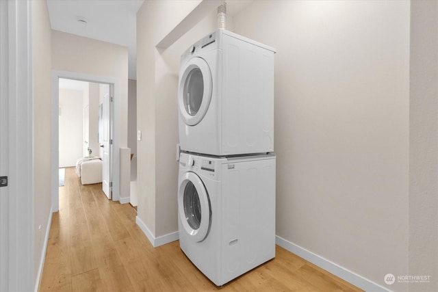 laundry room featuring stacked washer and clothes dryer and light hardwood / wood-style floors