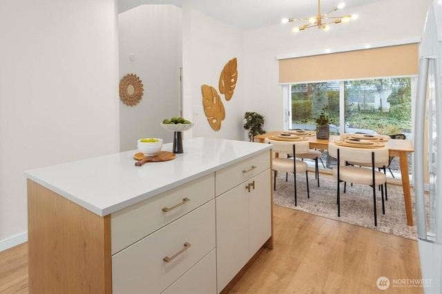 kitchen with an inviting chandelier, a center island, light hardwood / wood-style flooring, and white cabinets