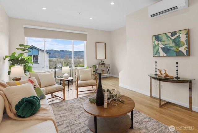 living room with a mountain view, light hardwood / wood-style floors, and an AC wall unit