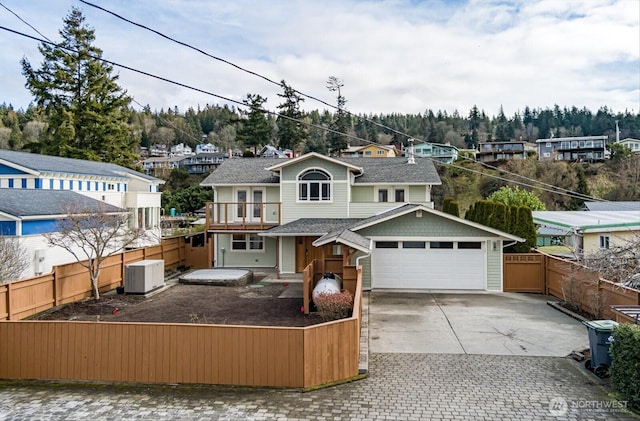 view of front of property with driveway, an attached garage, fence, and central air condition unit