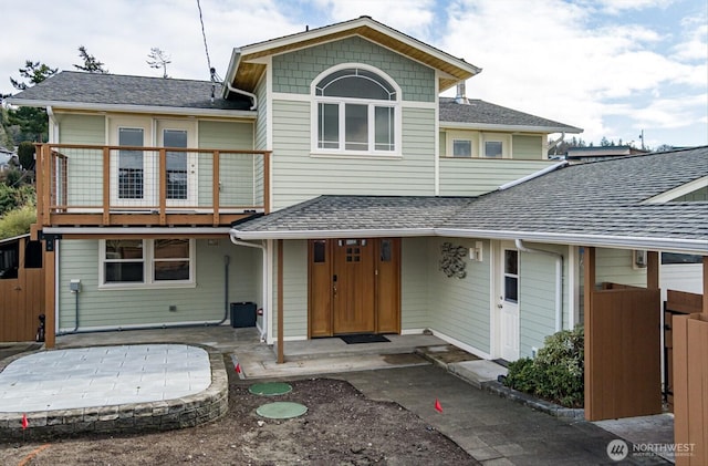 view of front of house featuring a shingled roof and a balcony