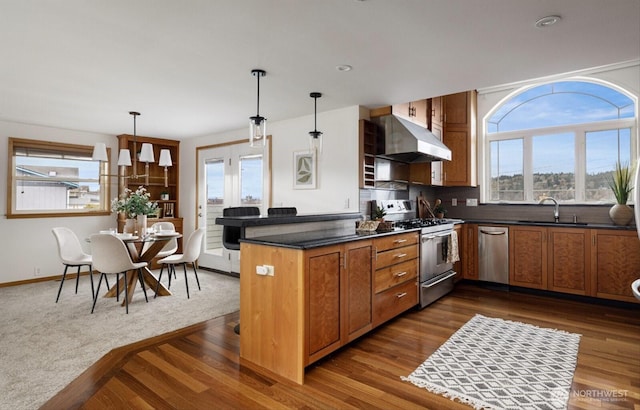 kitchen featuring appliances with stainless steel finishes, brown cabinetry, hanging light fixtures, and under cabinet range hood